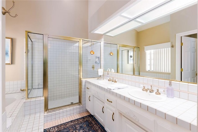 bathroom featuring a stall shower, tile patterned floors, a sink, and a bath