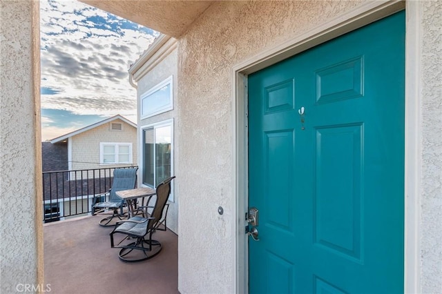 view of exterior entry featuring a balcony and stucco siding