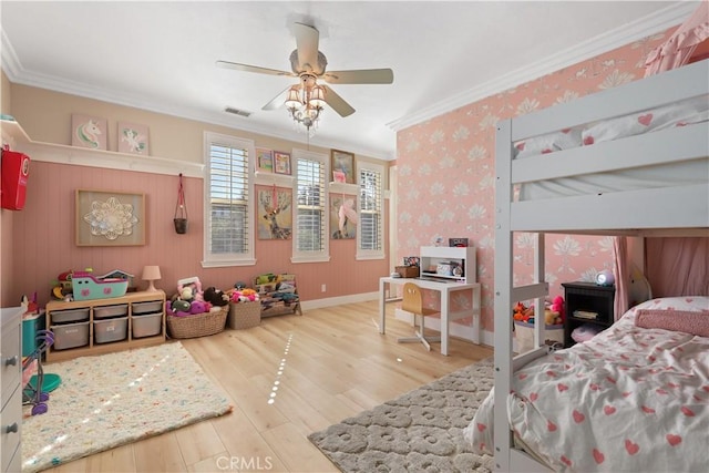 bedroom featuring visible vents, wallpapered walls, baseboards, ornamental molding, and wood finished floors