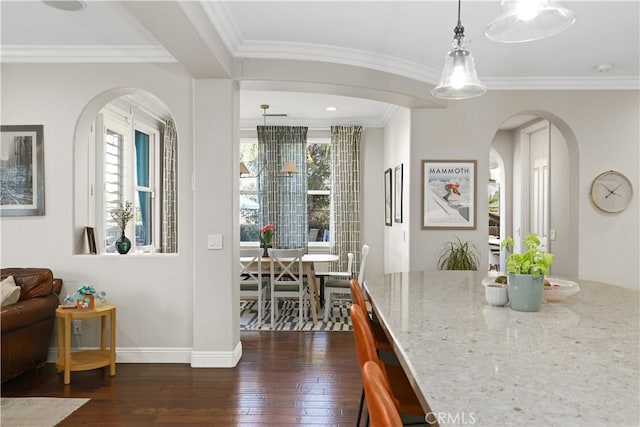 interior space with dark wood finished floors, crown molding, baseboards, and arched walkways