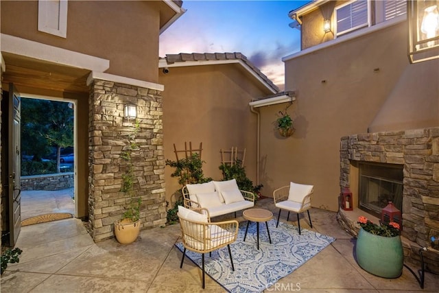 patio terrace at dusk with an outdoor living space with a fireplace