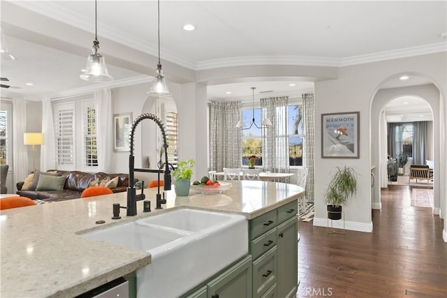 kitchen with green cabinets, crown molding, dark wood-style floors, and a sink