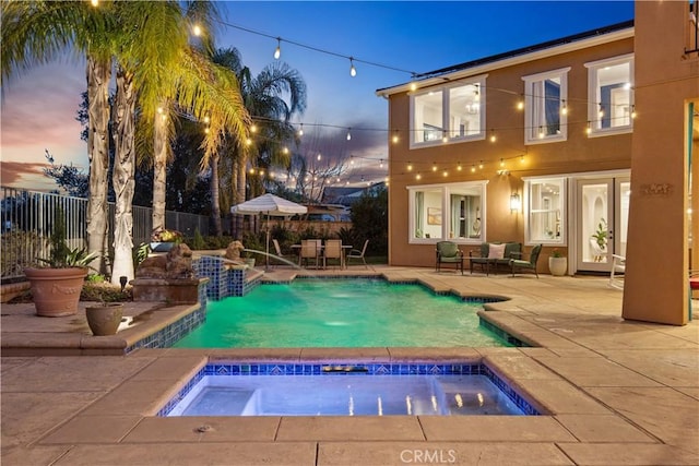 pool at dusk featuring an in ground hot tub, fence, a fenced in pool, and a patio