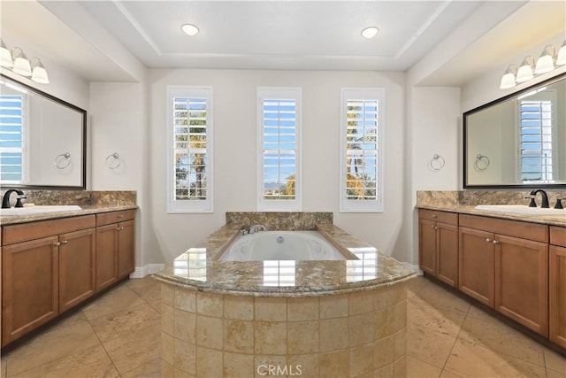 bathroom with a garden tub, two vanities, recessed lighting, and a sink