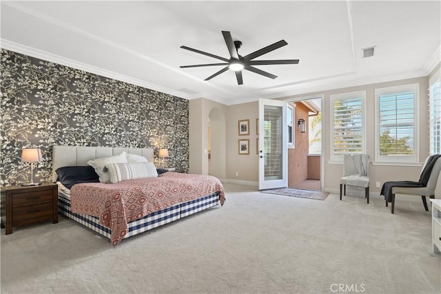 carpeted bedroom featuring baseboards, visible vents, a tray ceiling, arched walkways, and ornamental molding