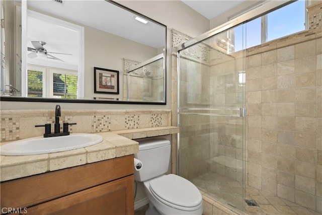 bathroom with vanity, toilet, a ceiling fan, and a stall shower