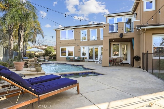 rear view of property with a patio, a balcony, fence, stucco siding, and french doors