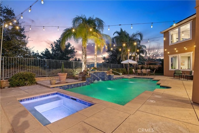 pool at dusk with a fenced in pool, a patio, an in ground hot tub, and a fenced backyard