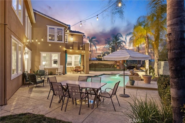 view of patio / terrace featuring outdoor dining area, a balcony, a fenced in pool, and fence