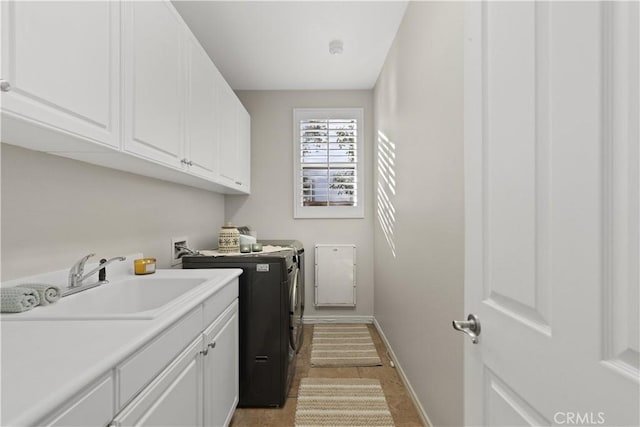 washroom with a sink, cabinet space, baseboards, and washer and clothes dryer