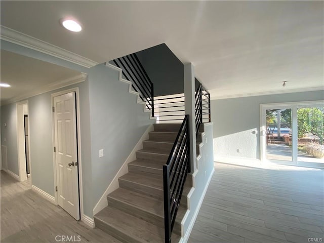 stairway with wood finished floors, baseboards, and ornamental molding