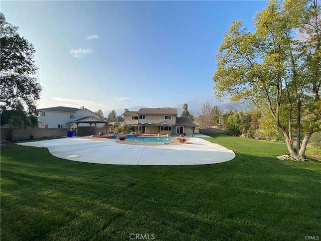 back of property featuring fence, a yard, a patio area, and an outdoor pool