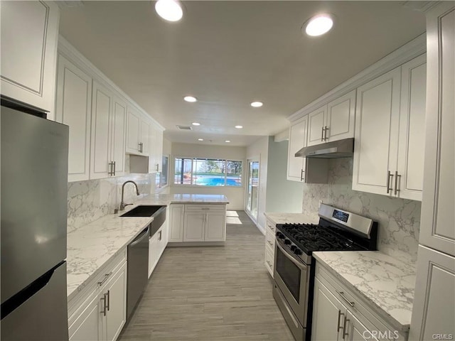 kitchen featuring a sink, white cabinetry, under cabinet range hood, and stainless steel appliances