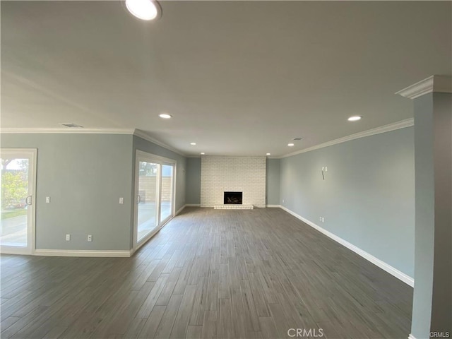 unfurnished living room with baseboards, a brick fireplace, a healthy amount of sunlight, and dark wood-style flooring