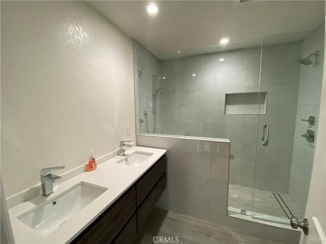 bathroom with a sink, double vanity, recessed lighting, and a shower stall