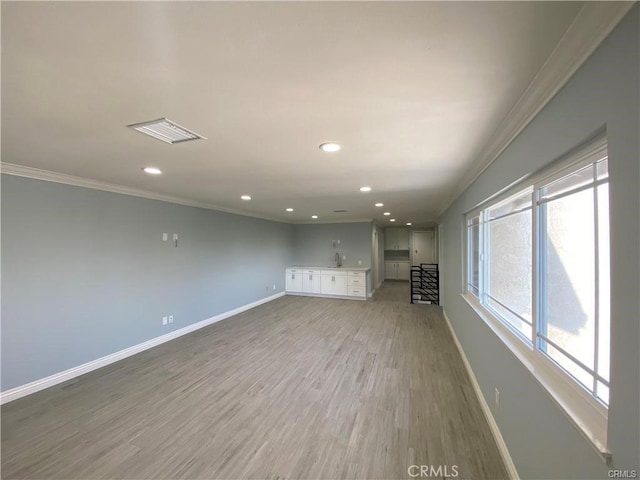 unfurnished living room featuring crown molding, visible vents, baseboards, and light wood finished floors