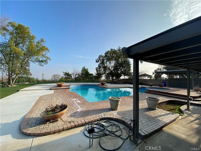 outdoor pool with a patio area, fence, and an in ground hot tub