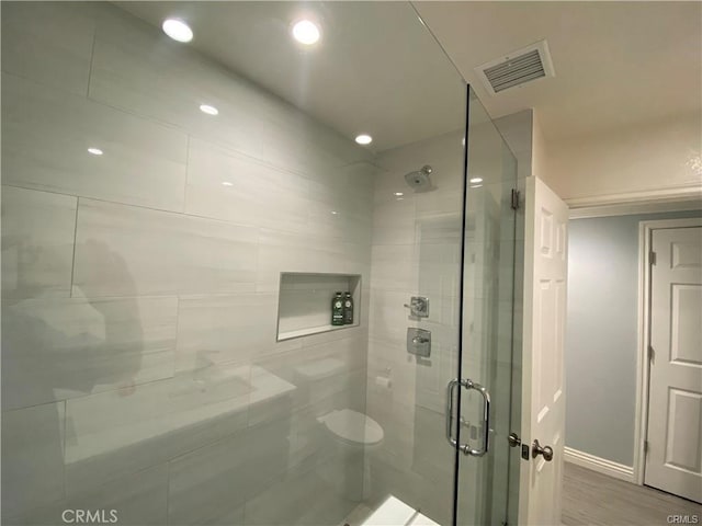 bathroom with wood finished floors, visible vents, baseboards, recessed lighting, and a shower stall