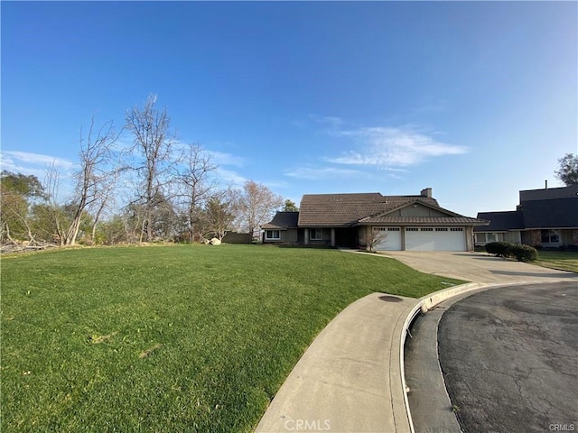 view of front of property with driveway, a front yard, an attached garage, a chimney, and a tiled roof