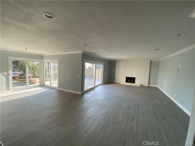 unfurnished living room with a wealth of natural light, dark wood-style flooring, a fireplace, and ornamental molding