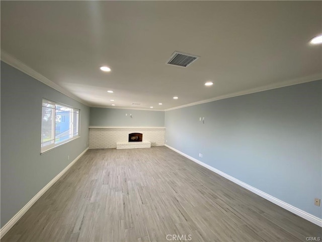 unfurnished living room featuring visible vents, wood finished floors, ornamental molding, and a fireplace