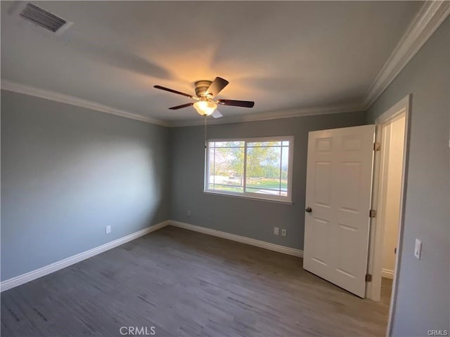 spare room featuring wood finished floors, baseboards, visible vents, and ornamental molding