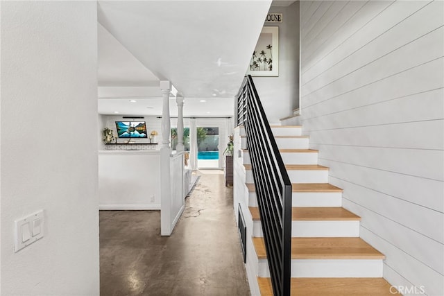 staircase with concrete floors and ornate columns