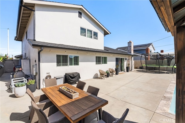 view of patio / terrace with grilling area, an outdoor fire pit, a trampoline, and fence