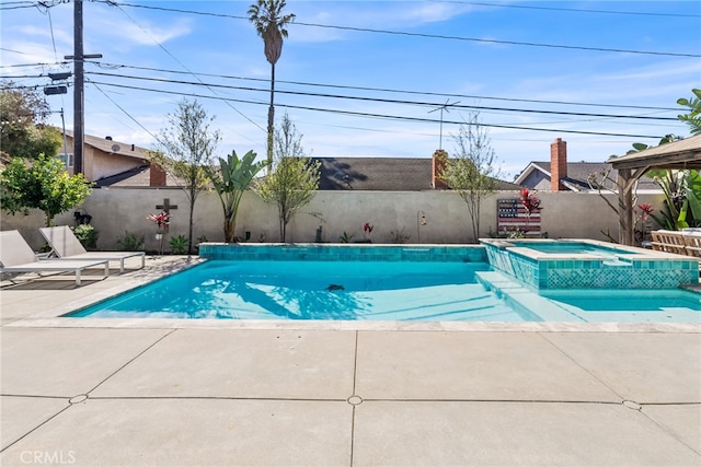 view of swimming pool featuring a patio, a fenced backyard, and a pool with connected hot tub