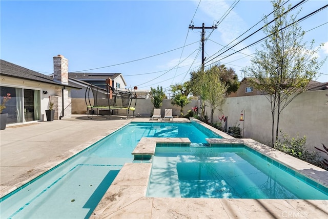 view of pool with a patio, a trampoline, a fenced backyard, and a pool with connected hot tub