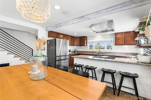 kitchen with light stone countertops, a peninsula, appliances with stainless steel finishes, and a breakfast bar area