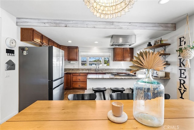 kitchen with open shelves, freestanding refrigerator, recessed lighting, a peninsula, and wall chimney exhaust hood