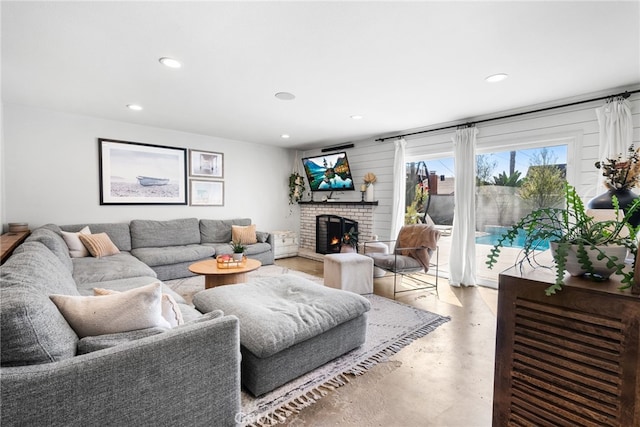 living area featuring finished concrete floors, recessed lighting, and a brick fireplace