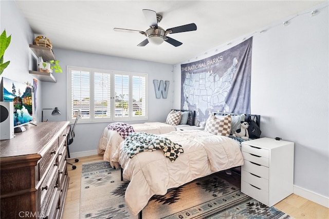 bedroom featuring light wood finished floors, a ceiling fan, and baseboards