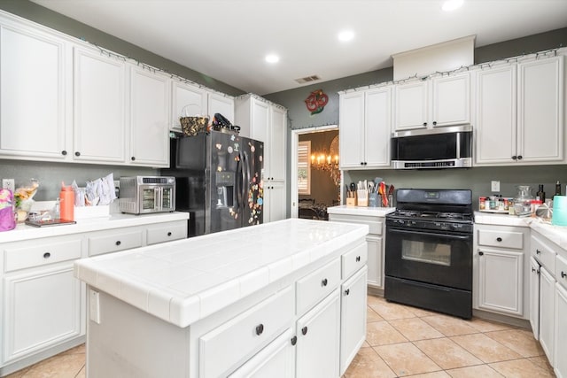 kitchen featuring tile countertops, visible vents, white cabinets, a center island, and black appliances