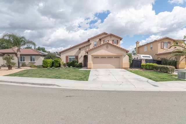 mediterranean / spanish house featuring an attached garage, fence, concrete driveway, stucco siding, and a front yard