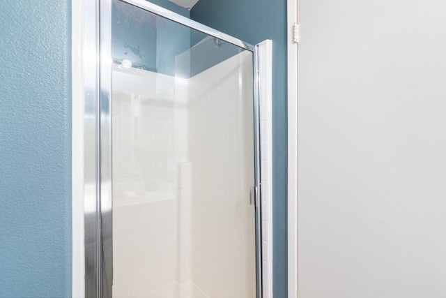 bathroom with a textured wall and a shower stall