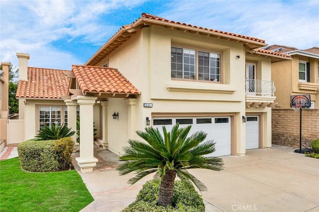 mediterranean / spanish-style house with driveway, a tiled roof, a garage, and stucco siding