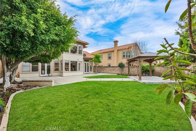 back of house featuring french doors, stucco siding, a lawn, a patio area, and a fenced backyard