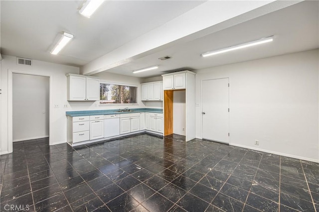 kitchen with baseboards, a sink, visible vents, and white cabinets