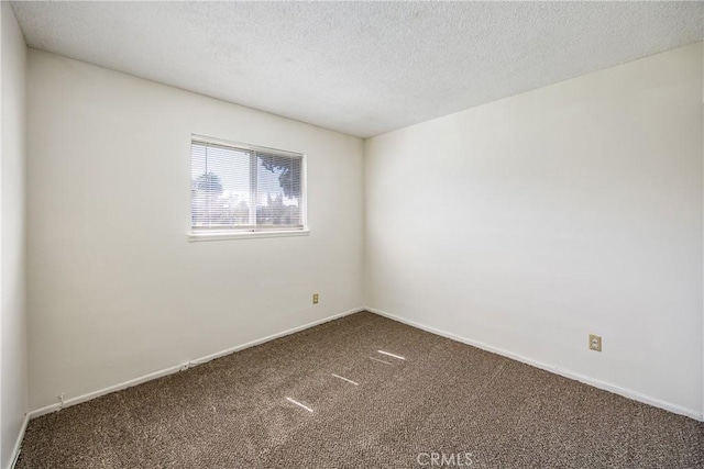 carpeted spare room featuring a textured ceiling and baseboards