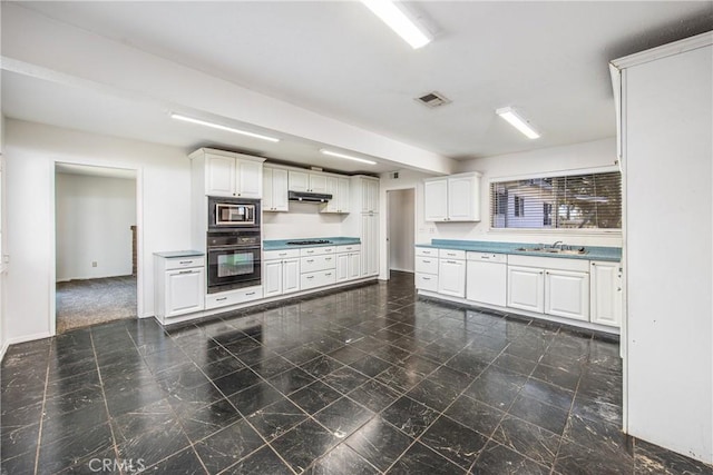 kitchen featuring under cabinet range hood, a sink, visible vents, white cabinetry, and black appliances