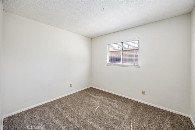 empty room with carpet, a textured ceiling, and baseboards