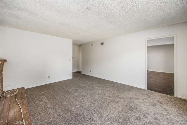 carpeted spare room featuring visible vents, a fireplace, a textured ceiling, and baseboards