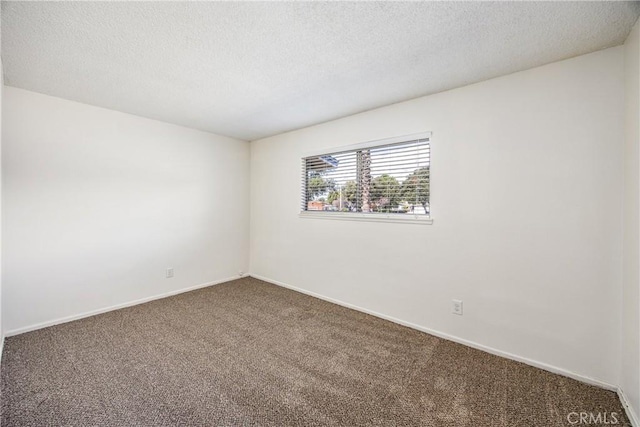 carpeted empty room with a textured ceiling and baseboards