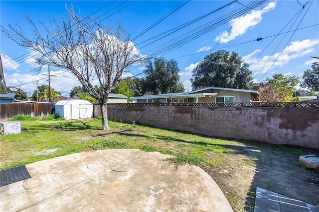 view of yard featuring a patio area, a fenced backyard, an outbuilding, and a shed