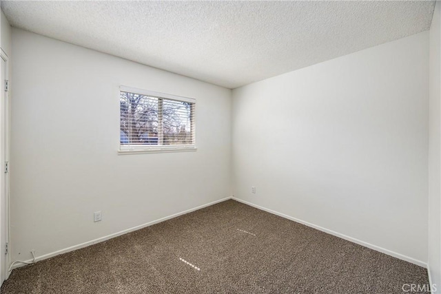 unfurnished room featuring baseboards, dark carpet, and a textured ceiling