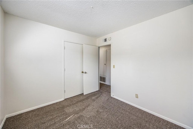 unfurnished bedroom featuring a textured ceiling, carpet floors, visible vents, and baseboards