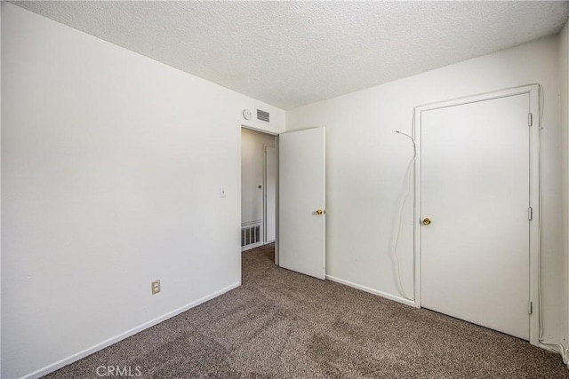 unfurnished bedroom featuring a textured ceiling, carpet, visible vents, and baseboards