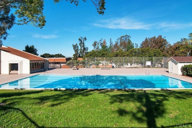 pool featuring a patio area, fence, and a lawn